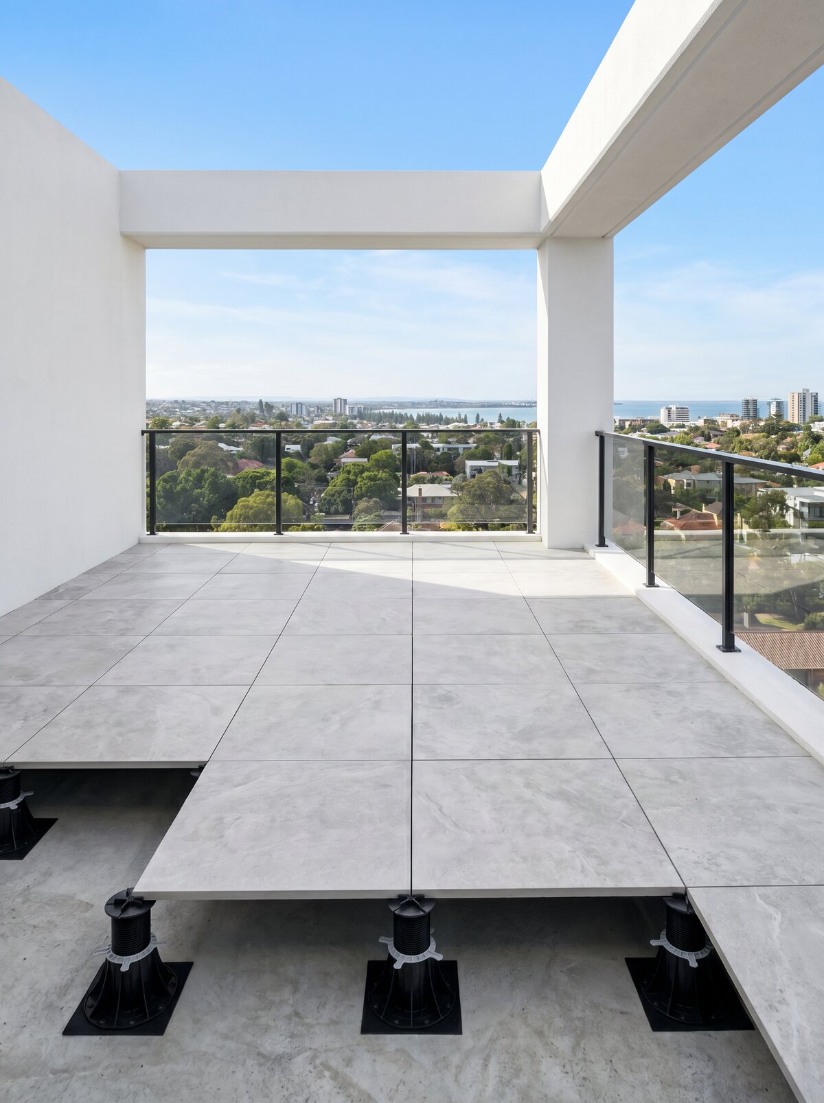 Modern balcony with a raised deck terrace made of light gray pavers