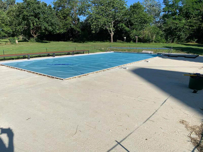 Home swimming pool with blue protective roller shutter in a large surroundings
