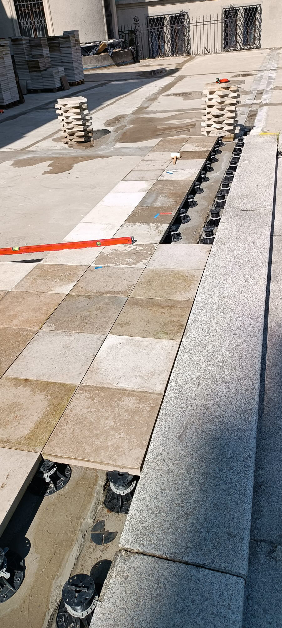 Laying beige terrace pavers on black pedestals
