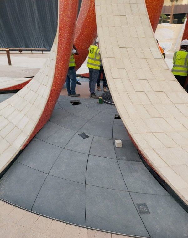 Installation of stone flooring around the arched sculpture at Expo 2020