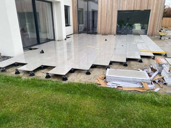 Construction of a raised deck terrace on the ground on pedestals with pavers in a backyard terrace