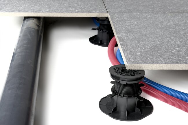 Water and electrical installation routed under a raised deck terrace with pedestals