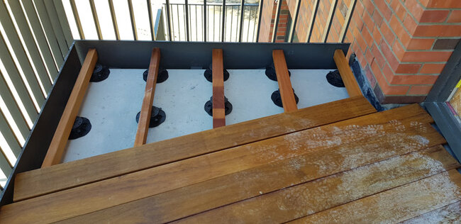 Elevated terrace construction on a balcony with adjustable pedestals