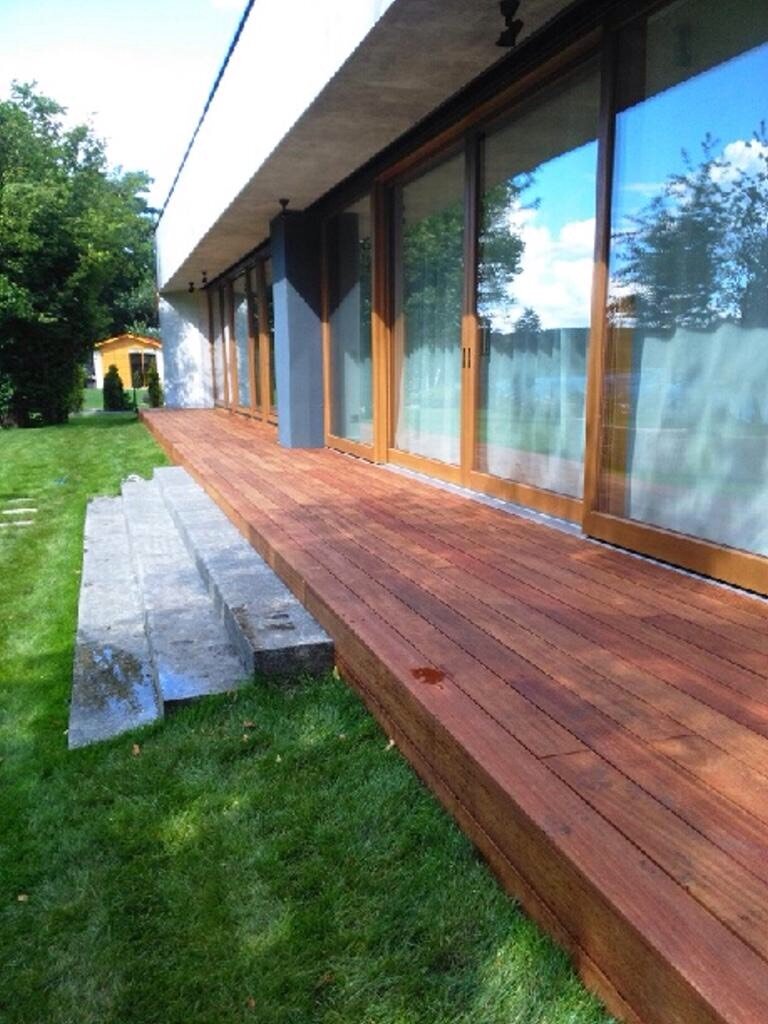 Terrace arrangement with gres tiles, rattan chairs, and plants.