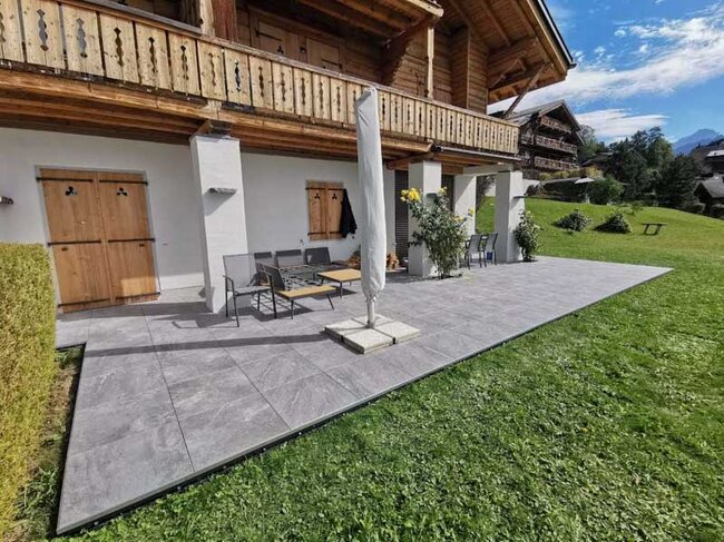 Elevated wooden terrace with stairs and railing by the house