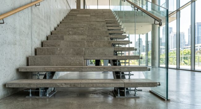 Modern stone stairs and glass railing in an industrial interior