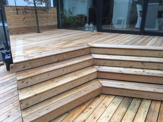 Modern wooden terrace with corner stairs and glass sliding doors