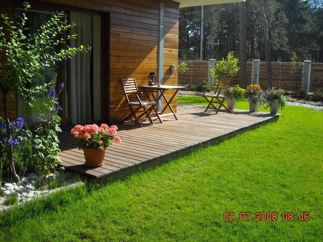 Wooden terrace in the garden with terrace furniture and flowers