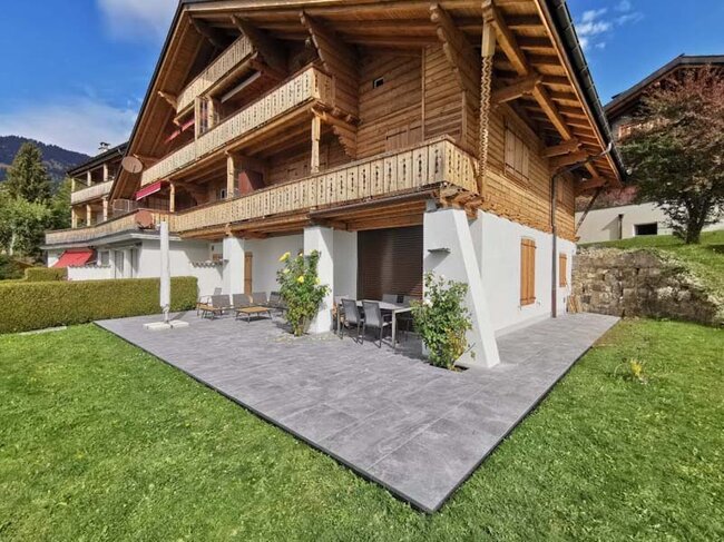 Elevated terrace with dark gres tiles at a wooden house in alpine style