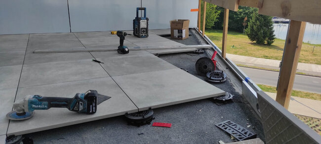 Installation of gres tiles on pedestals on a roof covered with torch-applied waterproofing membrane