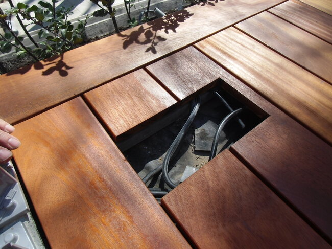 Inspection hatch in a wooden terrace providing access to electrical installations