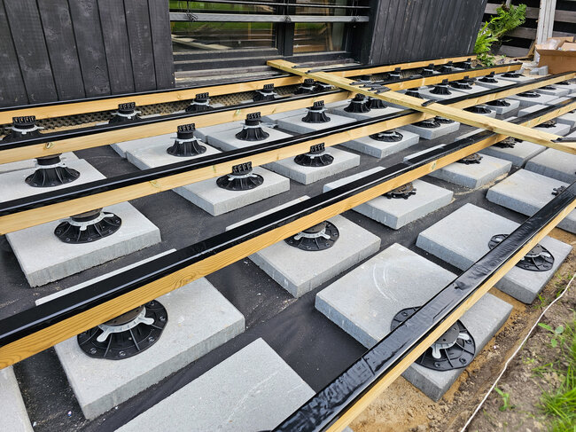 Deck substructure made of wooden joists on pedestals and concrete pavers