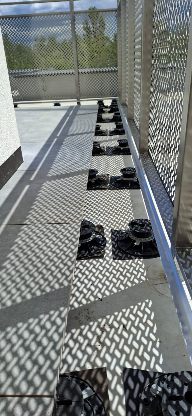 Adjustable pedestals under terrace pavers at the railing