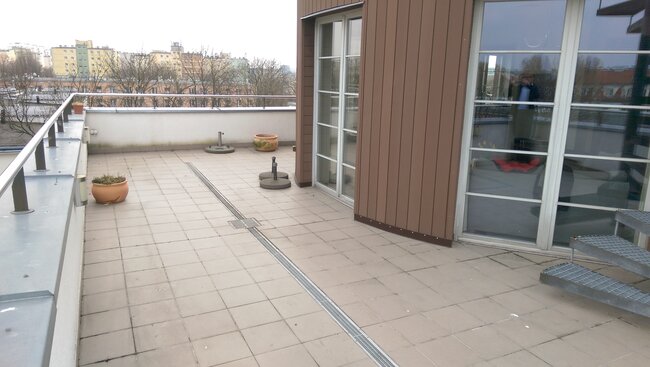 Large terrace with pavers and a linear drain on the roof of the building