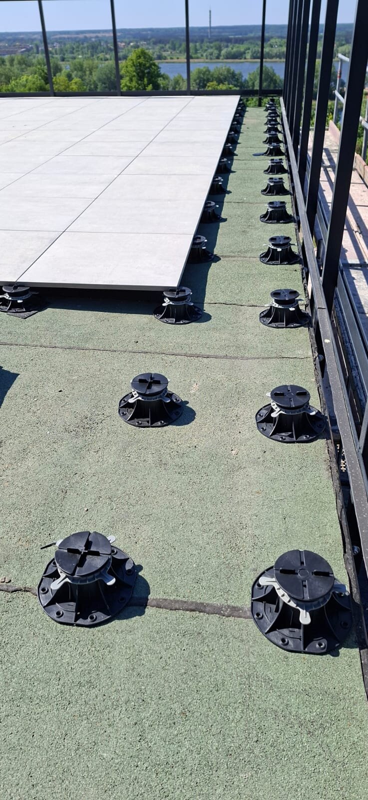 Installation of ceramic pavers on adjustable pedestals on a rooftop terrace