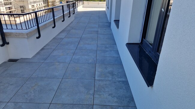 Adjustable pedestals are placed and pavers are laid on a raised deck terrace.