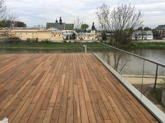 Long wooden terrace on a balcony with a glass balustrade