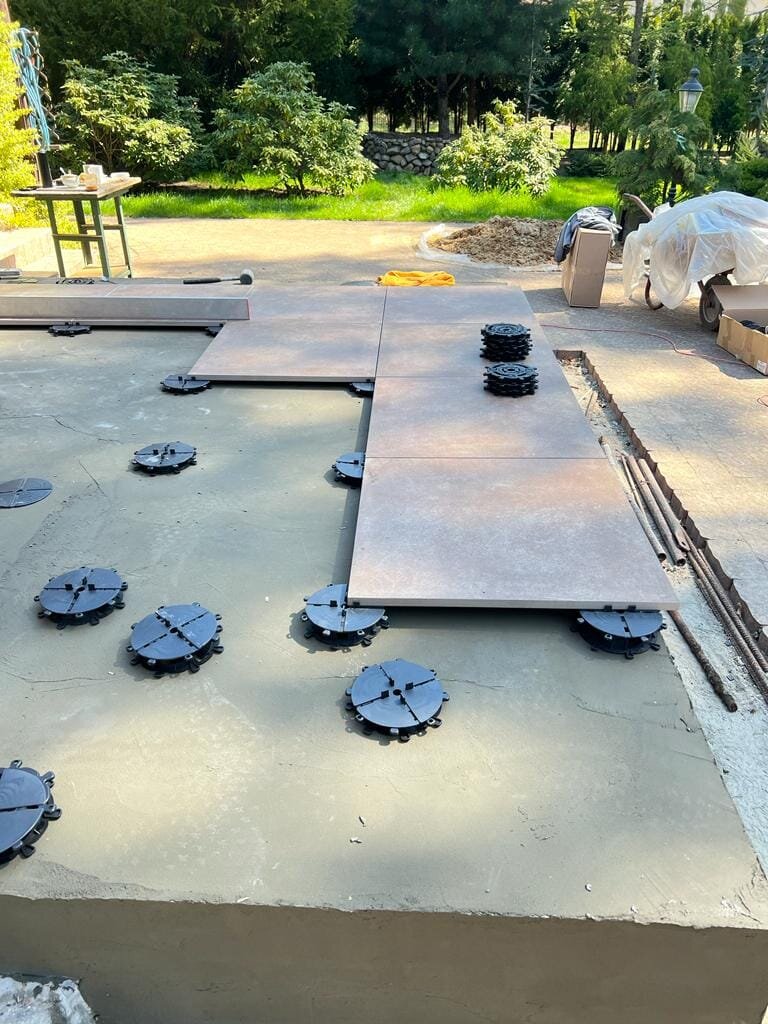 Laying terrace pavers on black support pads in the garden