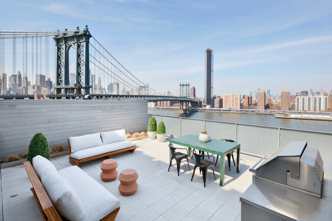 Luxury rooftop terrace with furniture and a view of the Manhattan Bridge