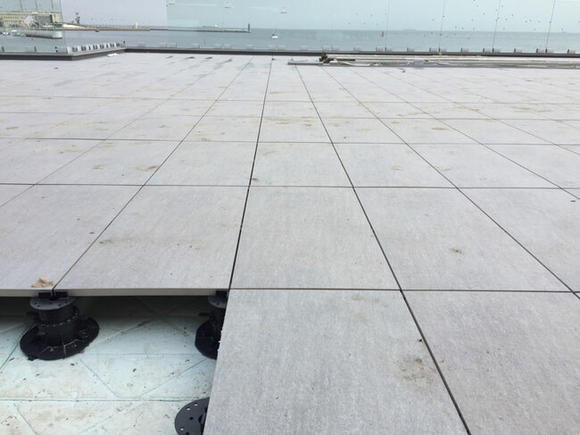 Installation of light gres tiles on terrace pedestals with a sea view