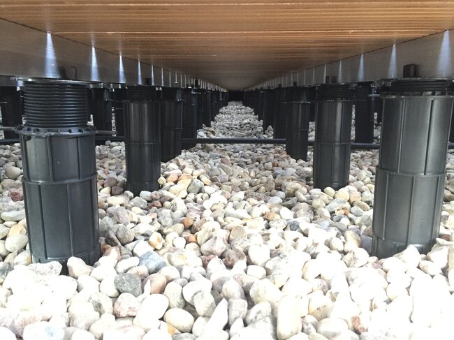 View under the terrace of tall adjustable pedestals arranged on gravel