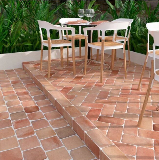 Terracotta terrace with garden furniture and greenery in the background