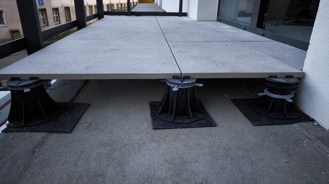 Raised deck terrace with 60x60x2 cm ceramic pavers during installation.