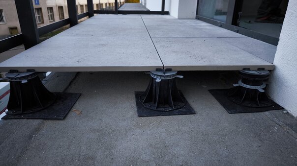 Raised deck terrace with 60x60x2 cm ceramic pavers during installation.