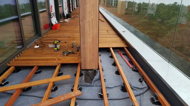Raised deck terrace with exotic boards on joists during installation.