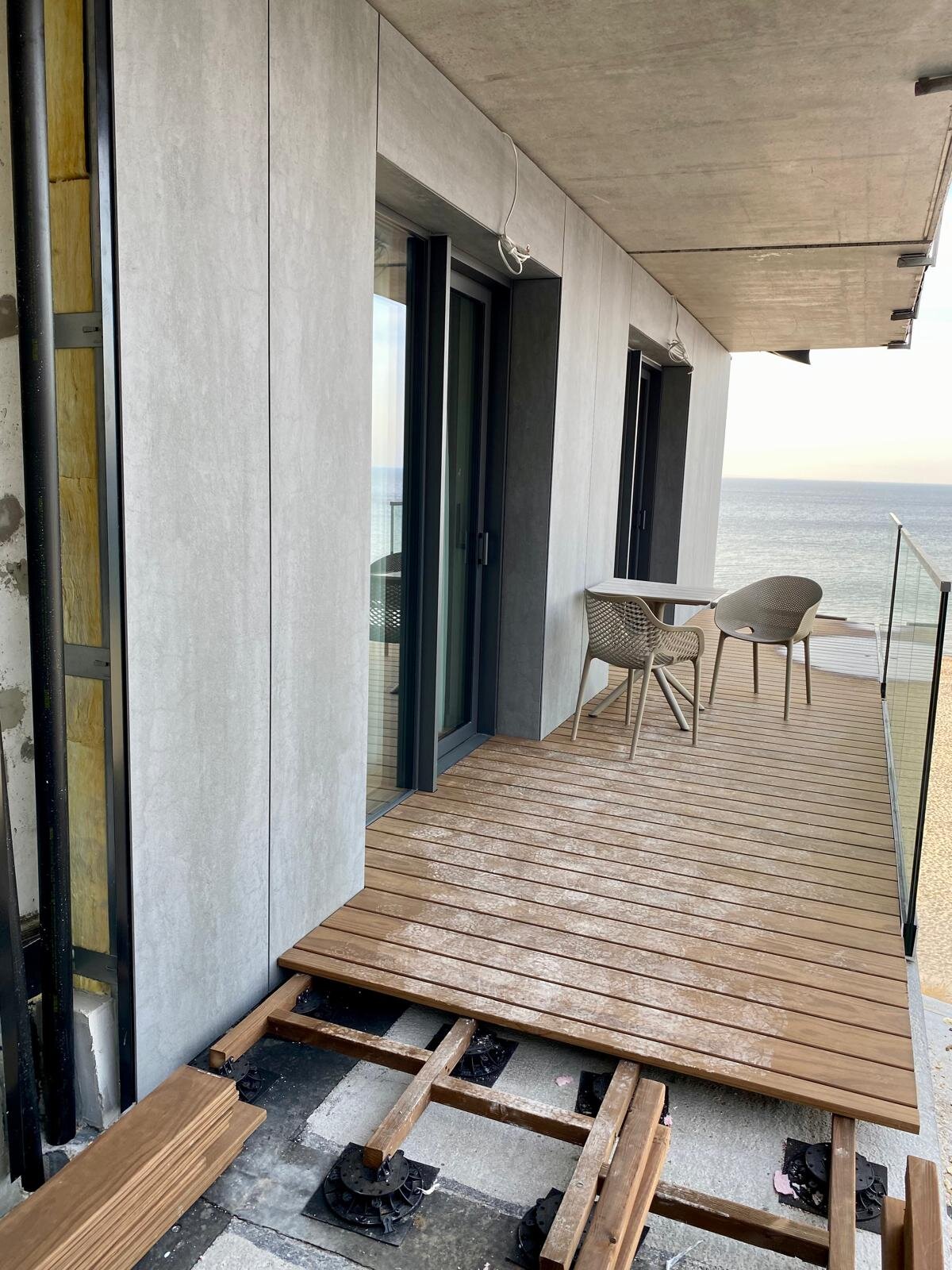 Raised deck terrace on a balcony with boards on joists during installation.