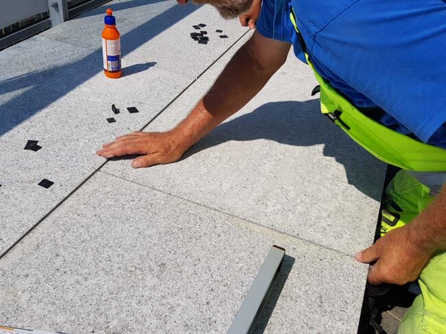 Man laying terrace pavers on adjustable pedestals solver on the terrace