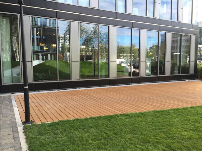 Ground-level terrace at an office building finished with composite decking boards