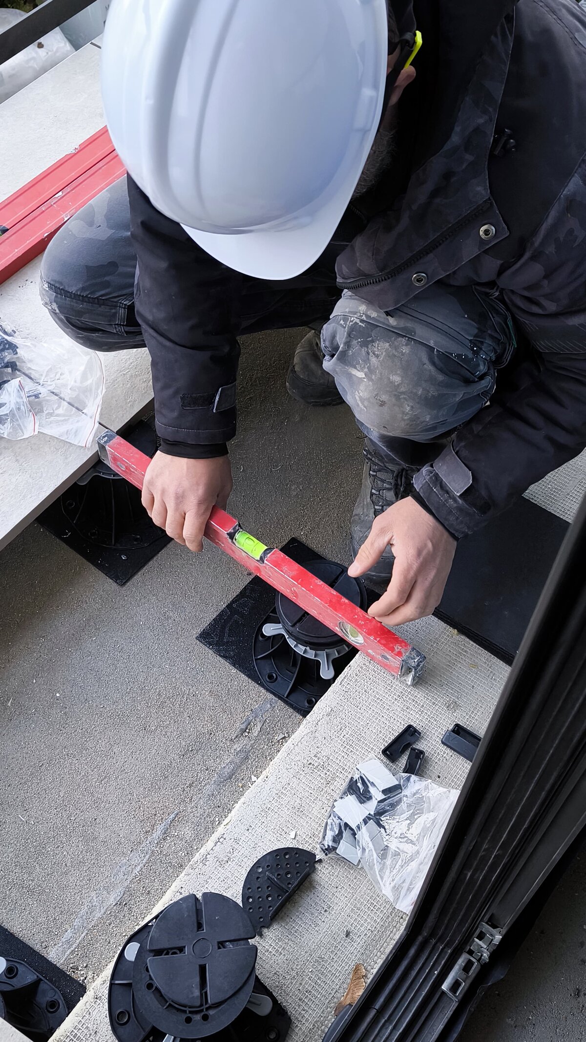 Installer leveling the terrace pedestal using a spirit level.