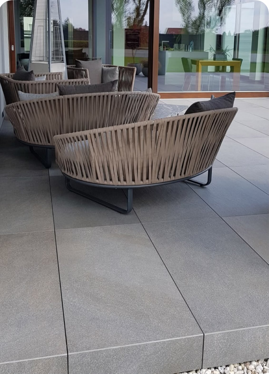 Modernist terrace with gres pavers equipped with woven garden furniture