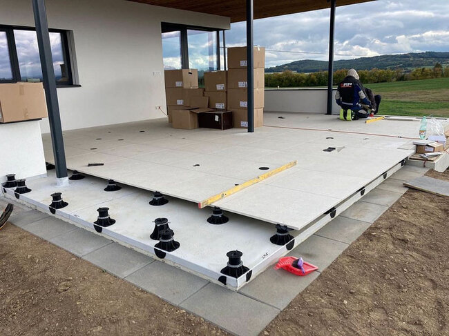 Installation of large-format gres tiles on adjustable pedestals at the house.