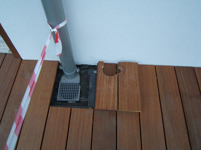 Installation of terrace boards around the downpipe and drainage inlet.