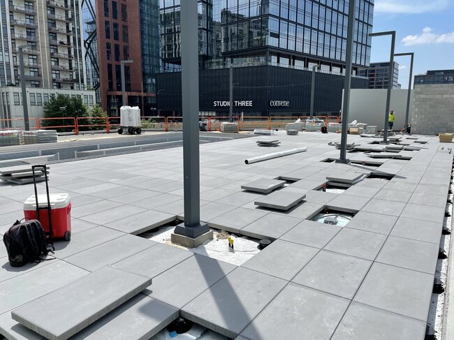 Laying pavers on pedestals on a green roof.