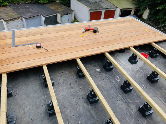 Laying a wooden terrace on joists and adjustable support pads.