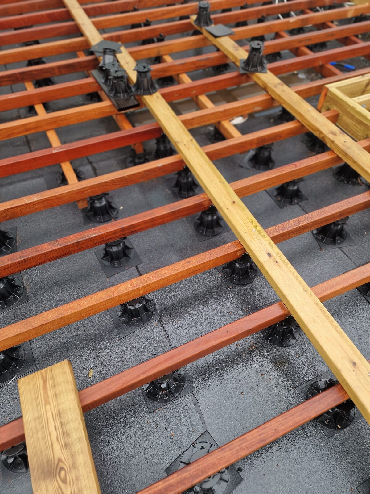 Installation of the wooden terrace substructure on adjustable pedestals.