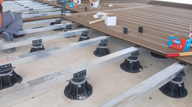 Construction of a composite deck terrace on adjustable support pads.