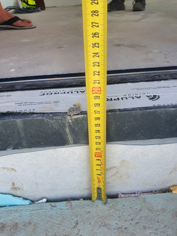 Measuring the height of the door threshold with a measuring tape.