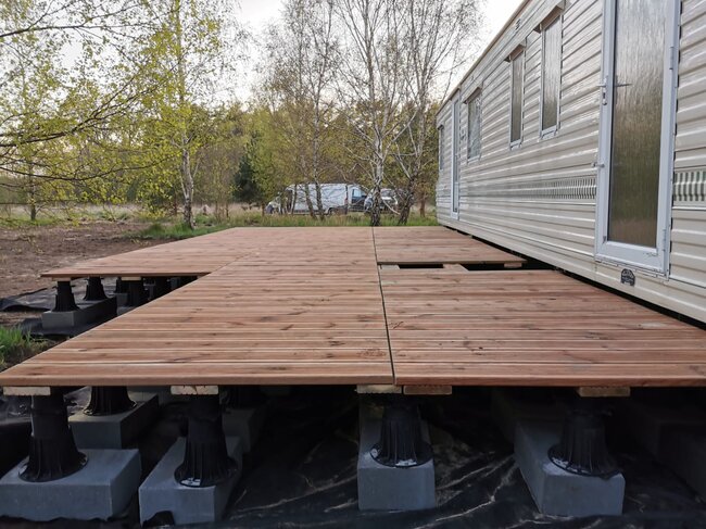 Construction of a wooden deck terrace on high adjustable pedestals.