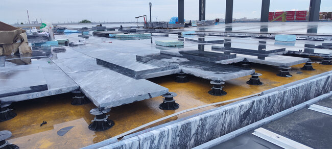 Installation of large stone pavers on adjustable pedestals on a flat roof
