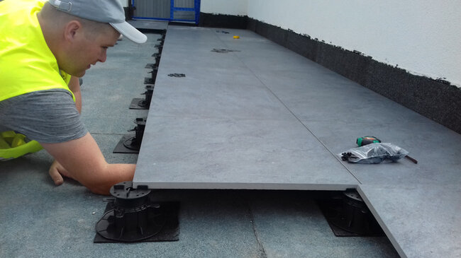 Installation of terrace pavers on adjustable pedestals - laying a raised deck terrace.