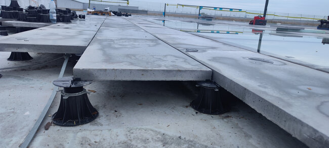 Installation of concrete pavers on adjustable plastic pedestals on the roof