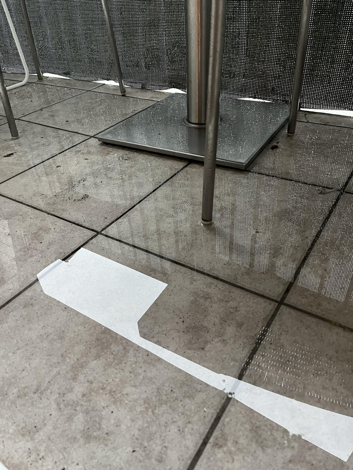 Puddle and standing water on balcony pavers under furniture