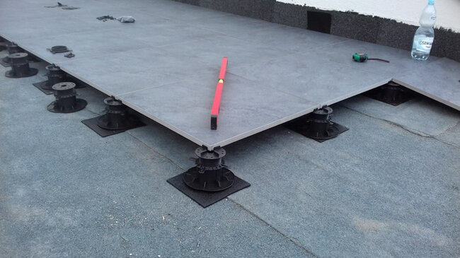 Adjustable pedestals laid on torch-applied roofing membrane with SBR rubber pads