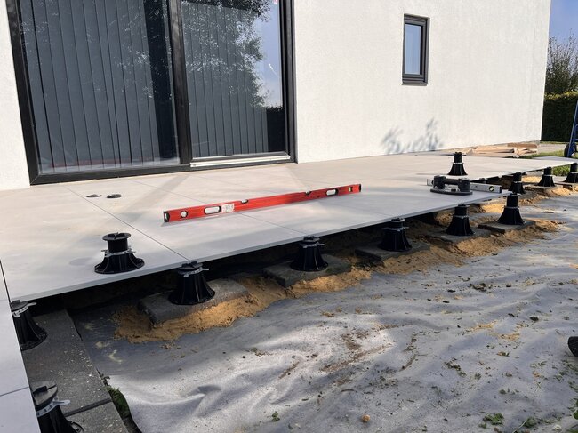 Installation of raised outdoor patio tiles using adjustable pedestal supports.