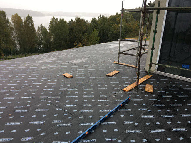 Flat roof under construction with waterproofing bitumous membrane installation.