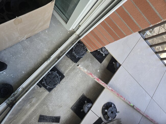 Raised floor pedestal system installation for balcony tile paving along the edge.